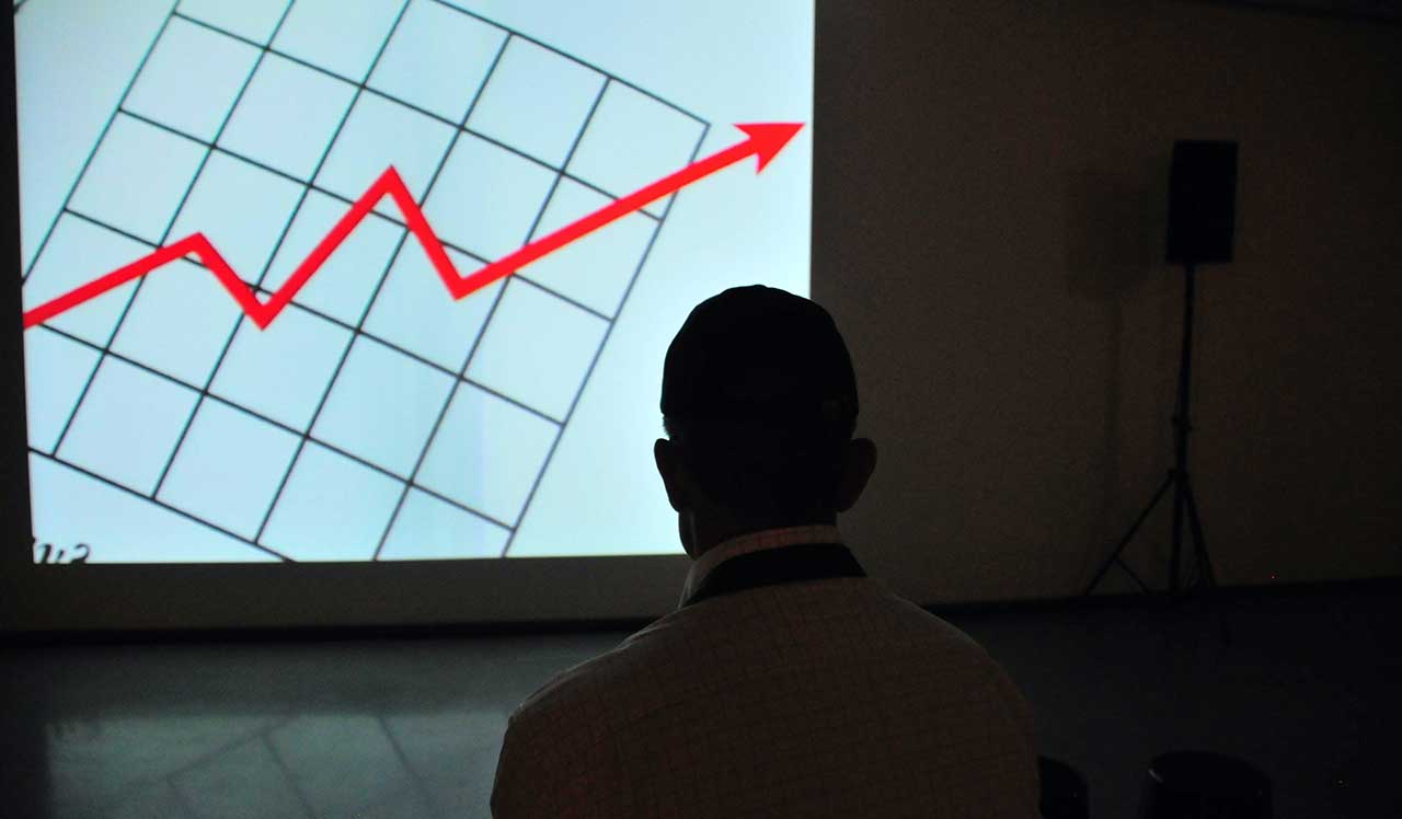 A man standing in front of a line chart, worried.  